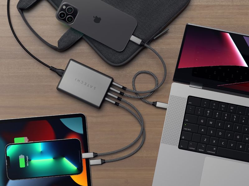 A lifestyle image showing a top-down view of the 165W Satechi GaN charger connected to two iPhones, iPad Pro and MacBook Pro