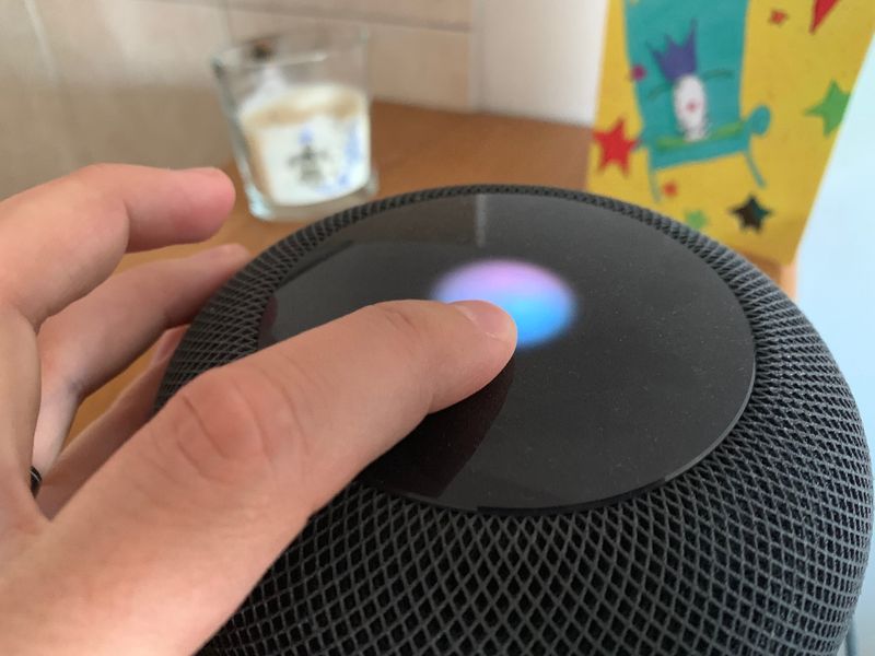 A photo showing a finger touching the HomePod top to pause a song