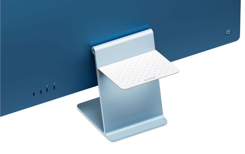 A promotional image from Twelve South showcasing its BackPack matte white aluminum shelf attached to the back of a blue 24-inch M1 iMac