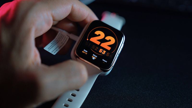 A photo of a hand holding an Apple Watch Series 6 with a white Sports band