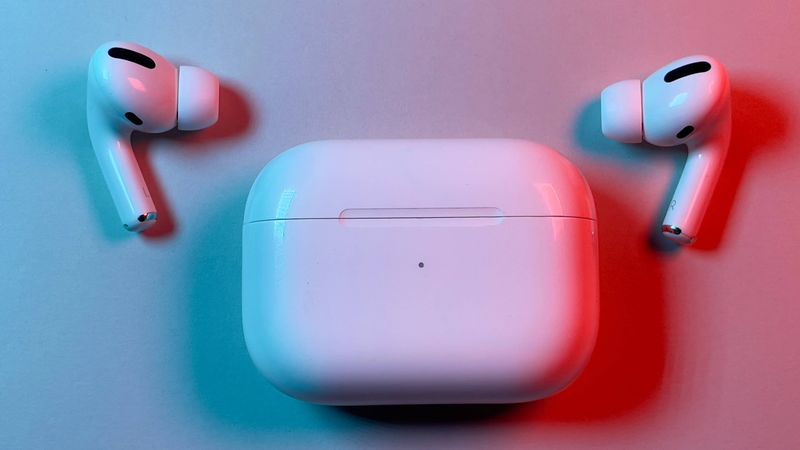 AirPods Pro earbuds lying next to a charging case with the lid closed