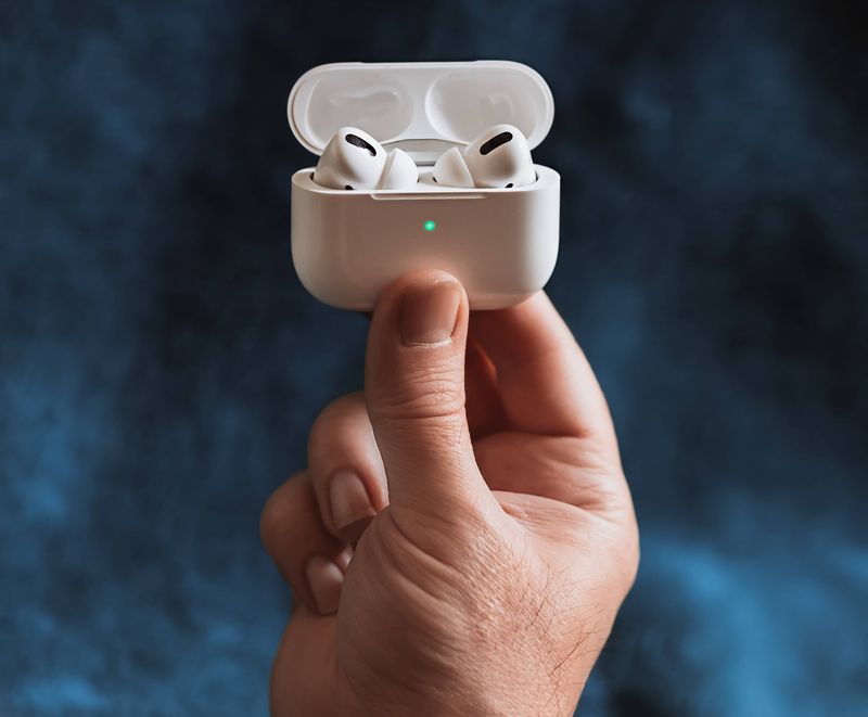 A male hand holding a charge case for AirPods Pro with the earbuds inside and the lid open
