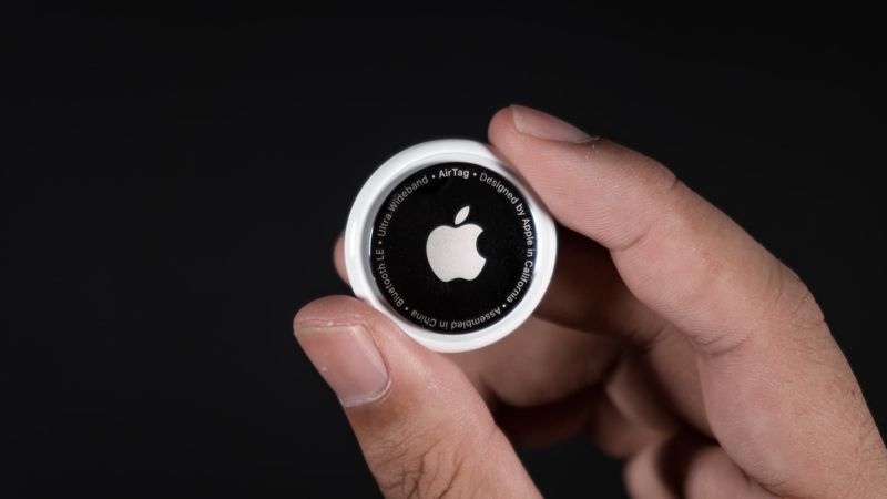 Holding an AirTag in hand on a black background
