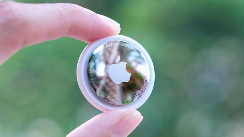 A closeup photograph of an Apple AirTag being held between a person
