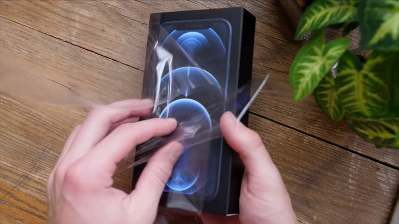 A still image from an iPhone 12 unboxing video that shows unwrapping the plastic wrapping of Apple