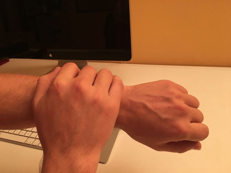 A hand covering an Apple Watch on the wrists with a palm
