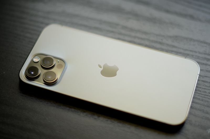 A gold iPhone 12 Pro Max laid face down on a wooden table
