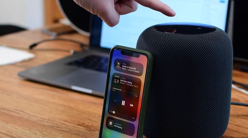 A photo showing a male finger pointing at the touch surface of the HomePod wireless speaker