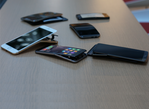 Consumer Reports (bent phones scattered on table)